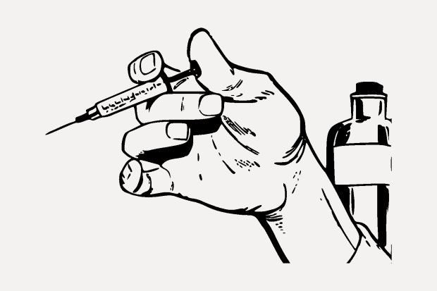 hand with syringe, poised to inject. A medicine bottle sits in the background. 